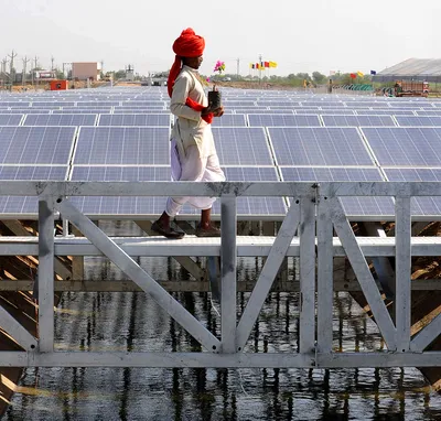 an indian worker crosses solar panel canal in india